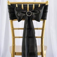 a chair with a black bow tied to it's back and gold trim around the seat