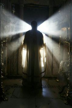 a man standing in front of a light that is shining down on him and his cloak