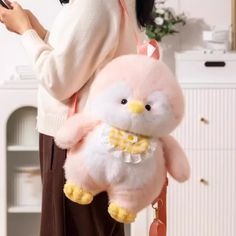 a woman holding a pink stuffed animal in her hand and looking at her cell phone