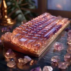 a keyboard covered in pink crystals on top of a wooden table next to a potted plant