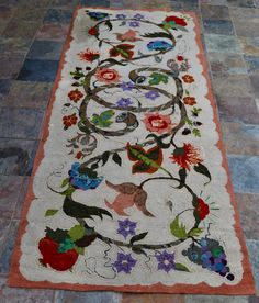 the rug is on the floor and has flowers all over it with an orange border