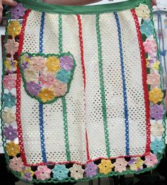 a woman is holding a crocheted bag with flowers on the front and sides