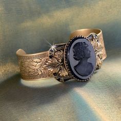 "Don't let anyone know this isn't a family heirloom. In time, and because of its association with you, it will become one. A circa 1930s art glass cameos rests upon acanthus leaves, symbol of life and vitality. Behind it, a frame of black enamel and marcasite stones is mounted on a wide bracelet band with Florentine tracery. In the early days of Sweet Romance Jewelry Mfg, I bought caches of glass elements that had been made in Austria, Germany and Czechoslovakia between the world wars. I bought Victorian Bracelet, Cameo Bracelet, Symbol Of Life, Jewelry Victorian, Slide Bracelet, Acanthus Leaves, Art Deco Bracelet, Antique Bracelets, Bracelet Wedding