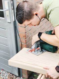 a man sanding a piece of wood on top of a wooden bench with a power drill