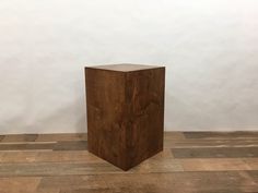 a wooden block sitting on top of a hard wood floor next to a white wall