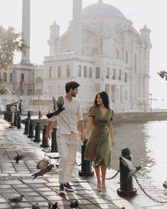 a man and woman walking down the street with pigeons