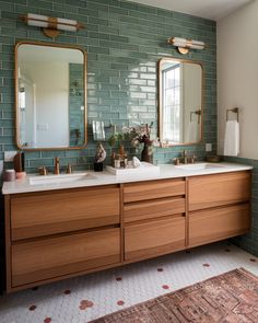 a bathroom with two sinks, mirrors and a rug in front of the sink area