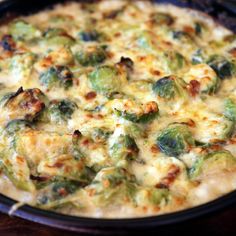 a casserole dish with broccoli and cheese in it on a wooden table