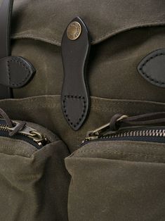 the back pocket of a green bag with zippers on it and a black leather handle