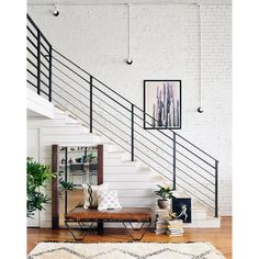 a room with a bench, books and pictures on the wall next to some stairs