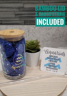 a glass jar filled with blue candies next to a card and succulent plant