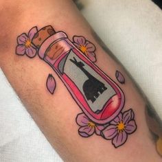 a tattoo with a bottle and flowers on it