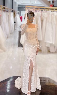 a woman taking a selfie in front of wedding dresses at the bridal shop