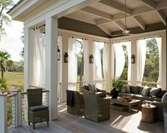 a covered porch with wicker furniture and large windows