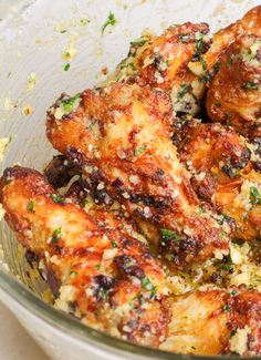 a glass bowl filled with chicken wings covered in parmesan cheese and seasoning