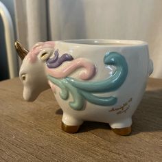 a ceramic cup shaped like a unicorn's head on top of a wooden table