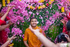 a man is surrounded by pink flowers and confetti as he poses for the camera