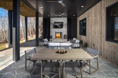 an outdoor living room with stone flooring and wood paneled walls, along with large windows