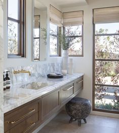 a bathroom with marble counter tops and two sinks in front of a large window that looks out onto the trees outside