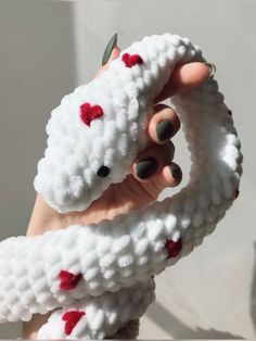 a person holding up a fake white snake with red hearts on it's tail