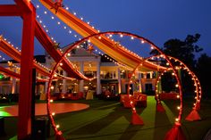 an outdoor event with red and orange decor, lights and decorations on the grass at night