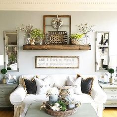 a living room filled with white furniture and lots of plants on top of the table