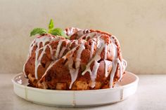 a bundt cake covered in icing and drizzled with mint leaves