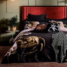 a bed with black and pink comforters in a bedroom next to a red headboard