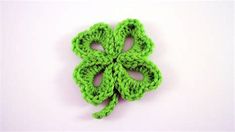 a crocheted green clover brooch sits on a white surface