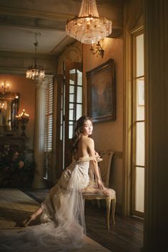 a woman sitting on top of a chair next to a chandelier in a room