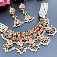 Beautifully handcrafted navrattan choker necklace in 22ct hallmarked gold along with matching earrings. The necklace weighs 55 GMs including 16.21 GMs of stringing and hanging beads. The earrings weigh 14.08 GMs including 1.05 GMs of hanging beads. Festive Multicolor 22k Gold Bridal Necklace, Multicolor 22k Gold Kundan Necklace For Celebration, Multicolor 22k Gold Bridal Necklace For Celebration, Multicolor Cutdana 22k Gold Jewelry, Multicolor 22k Gold Cutdana Jewelry, Multicolor 22k Gold Jewelry With Cutdana, Ceremonial 22k Gold Multicolor Jewelry, Multicolor 22k Gold Bridal Necklace For Festivals, Multicolor 22k Gold Temple Necklace For Festivals