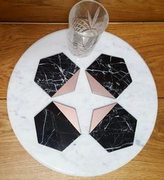 marble coasters with pink and black geometric designs on them sitting on a wooden table