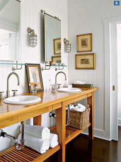 a bathroom with two sinks, mirrors and towels on the shelf in front of it