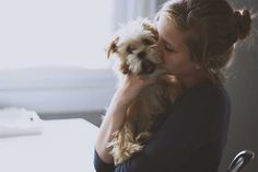 a woman holding a small dog in her arms with a quote on the side that says, we live in a family where everyone l've