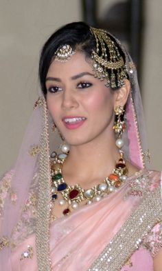 a woman in a pink dress and headpiece with pearls on her hair is smiling