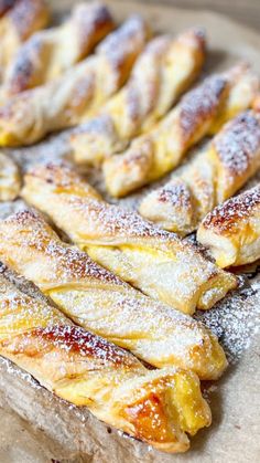 several pastries sitting on top of a wooden cutting board covered in powdered sugar