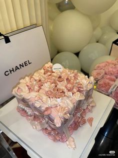 a box filled with pink flowers sitting on top of a white table next to balloons