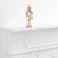 a wooden nutcracker standing on top of a white mantel above a fireplace