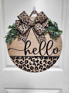 a leopard print door hanger with the word hello written on it and a bow