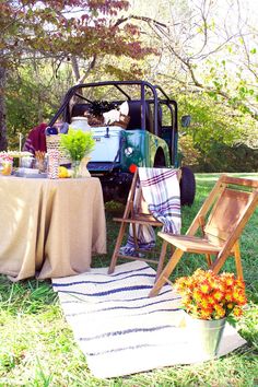 a table with flowers and an old truck in the back ground, set up for a picnic