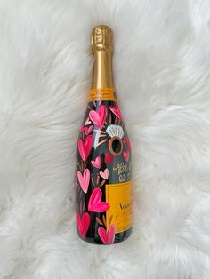 a bottle of champagne on a white furnishing with pink flowers and hearts painted on it