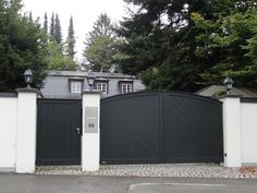 a gated driveway leading to a house with trees in the backgrouds