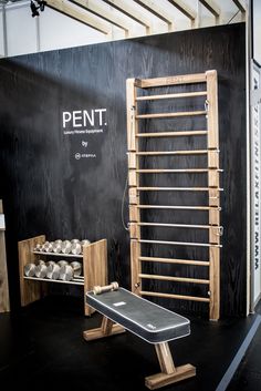 a bench and some dumbs in front of a black wall with the word pent on it