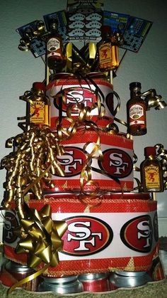 a cake made to look like a stack of beer cans with gold ribbon and bows on top