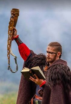 a man dressed in medieval clothing holding an open book