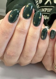 two hands with green nail polish holding each other's fingers and gold stars on them