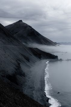 the ocean is covered in fog and low lying clouds