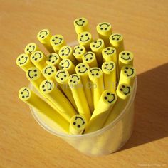 a cup filled with yellow smiley face pencils on top of a wooden table next to a