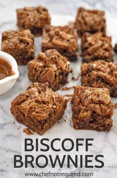 some brownies are sitting on a table with dipping sauce in the middle and one is cut into squares