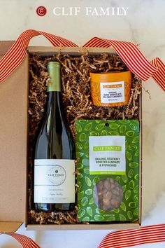 a bottle of wine and some nuts in a gift box with a ribbon around it